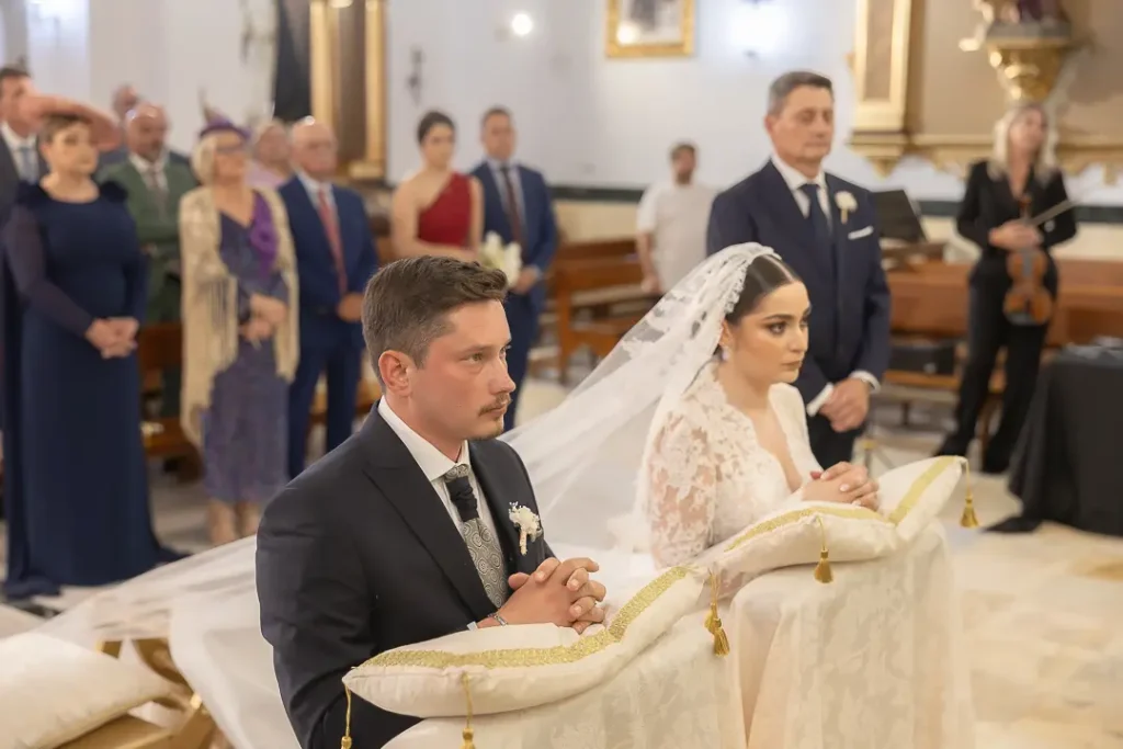 novios escuchando durante la ceremonia de rodillas