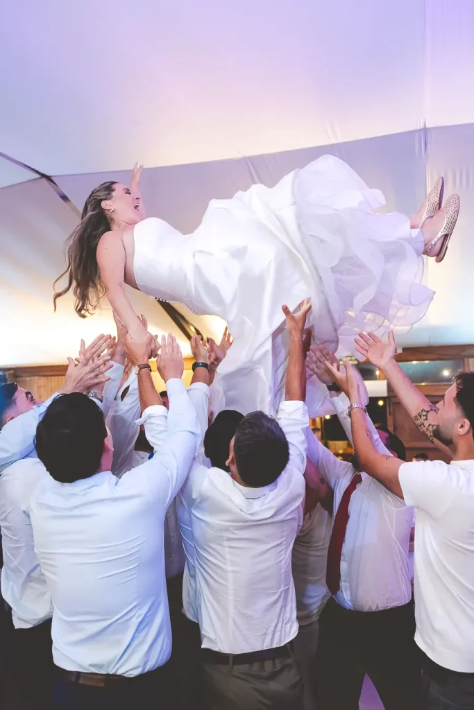 Los invitados levantando a la novia durante la fiesta.